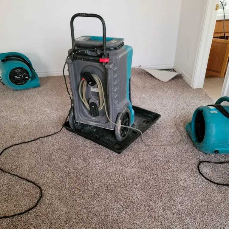 A dehumidifier and air movers positioned in a carpeted room during drying