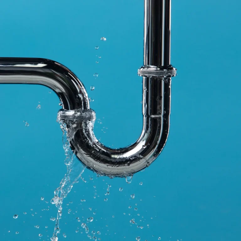 Water leaking from a metal drainpipe against a blue background
